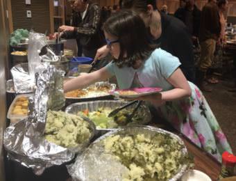 Zoe Trafton piles her plate with herring eggs at Sitka Tribe of Alaska's annual potluck, celebrating the cultural and ecological importance of the forage fish. STA is calling for the Board of Fish to reduce cap the guideline harvest level for Sitka's herring at 10%. (Photo by Emily Kwong/KCAW)