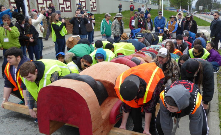 Volunteers lift the Raven totem pole at the totem pole raising in front of Gastineau Elementary School on Saturday.