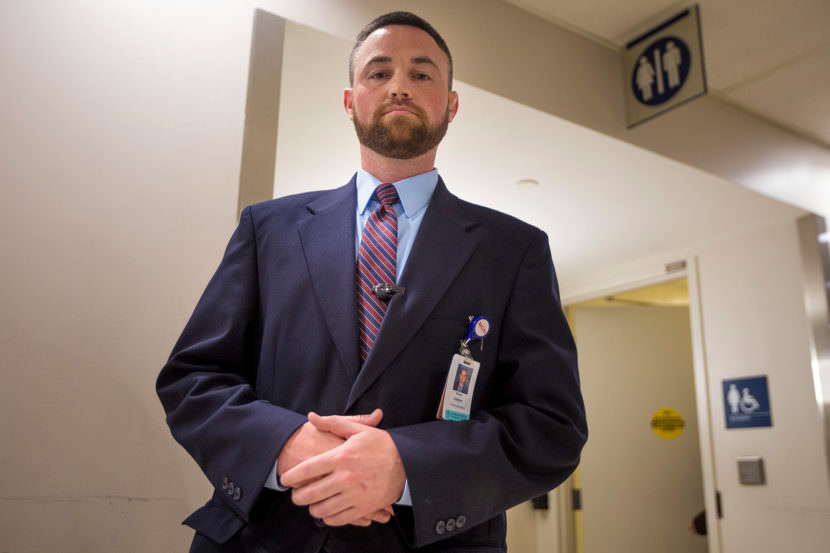 Ryan Curran, the day shift operations manager of police and security at Massachusetts General Hospital, stands in front of the bathrooms in the main lobby.