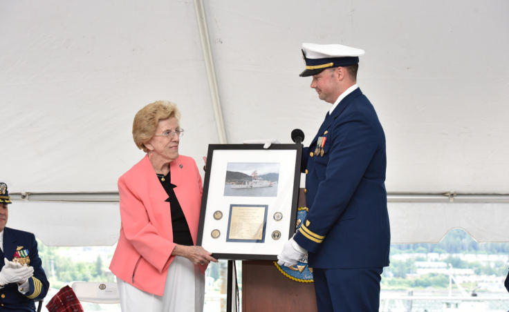 Carol Pugh, sponsor of the Coast Guard Cutter Bailey Barco, receives a commemorative photo of the vessel from Lt. Frank Reed, commanding officer of the cutter Bailey Barco during the vessel's commissioning ceremony in Juneau on June 14, 2017. Pugh is the great granddaughter of the vessel's namesake, Coast Guard hero and Gold Lifesaving Medal recipient Bailey Barco.