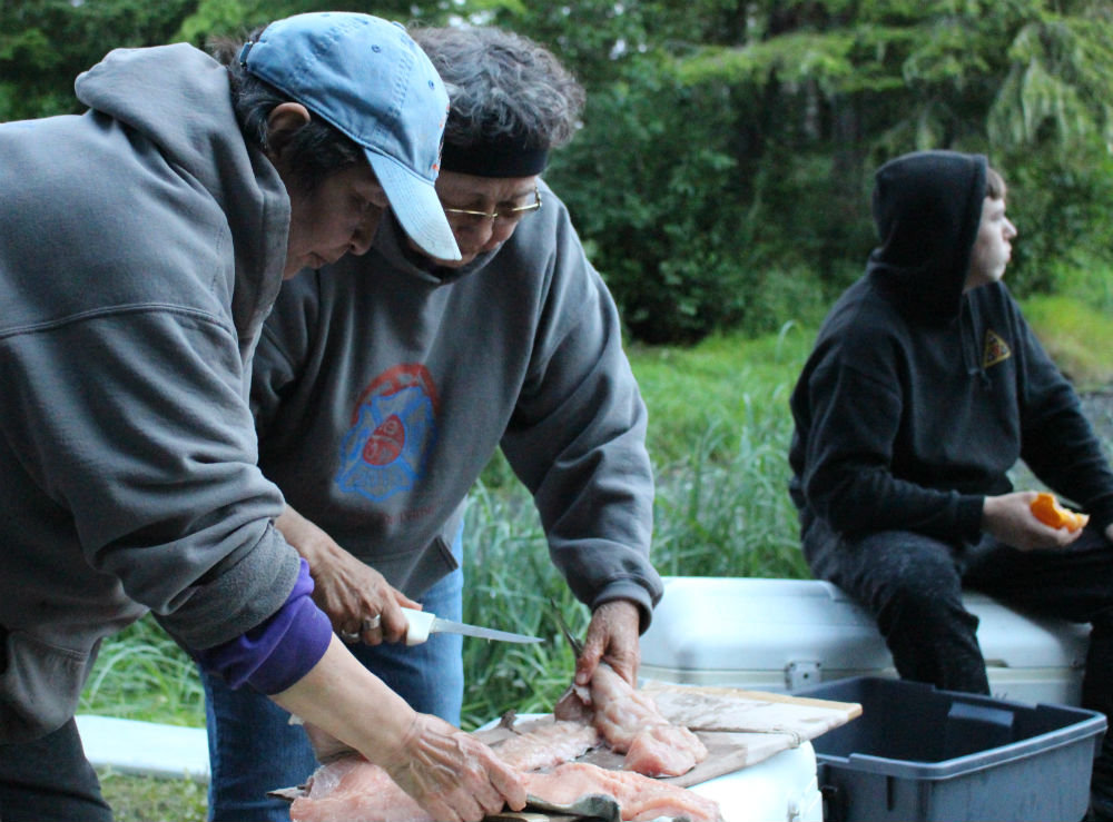 Myrna Demmert, left, works with her mom elder Ruth Demmert to filet dog salmon at Culture Camp. (Photo by Nora Saks/KFSK)