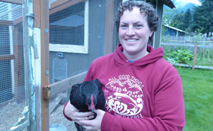 Sarah Dolan stands in front of her run and chicken coop holding a chicken on Saturday.