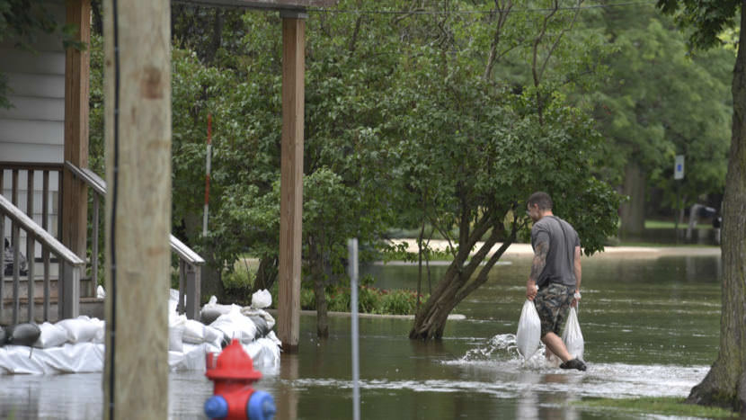 A man carries sandbags to reinforce the barrier he build to keep the floodwater from reaching his house in Gurnee, Ill., Friday. Illinois officials say flood damage north of Chicago is expected to worsen this weekend as water flows down rivers.