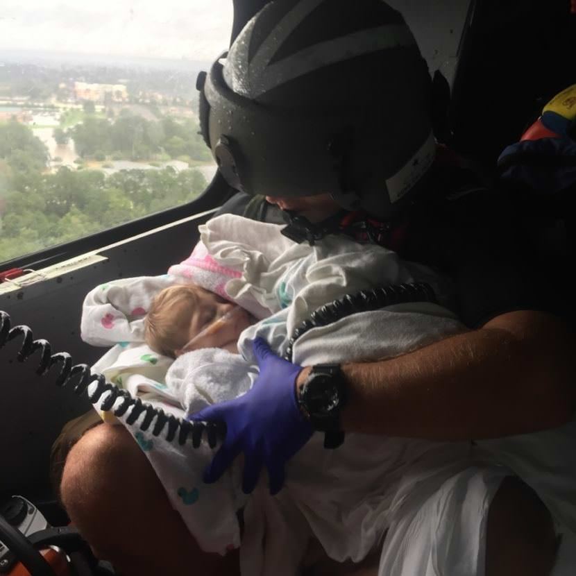 A Coast Guard aircrew assists an infant during the aftermath of Hurricane Harvey in the greater Houston Metro Area Aug. 29, 2017. The Coast Guard has pulled assets and resources from across the country to create a sustainable response force. (USCG photo by Petty Officer 2nd Class Chase Redditt.)