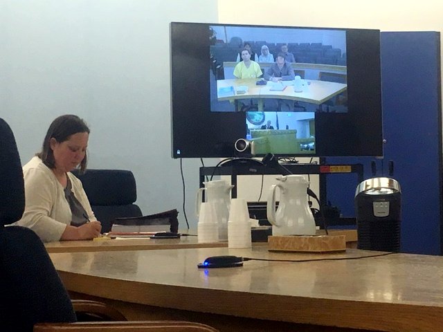 Defendant Reuben Yerkes, dressed in yellow scrubs, appeared in Sitka court via teleconference. He is displayed on a TV screen in the courtroom. Assistant district attorney Amanda Browning appeared in person.