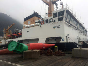 Buoys, chains and sinkers sit on the dock at Coast Guard Station Juneau with the buoy tenders Sycamore, Spar and Fir tied up in the background. (Photo by Matt Miller/KTOO)