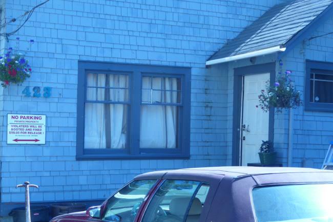 A blue house with the number 423. A red car sits in front of it.