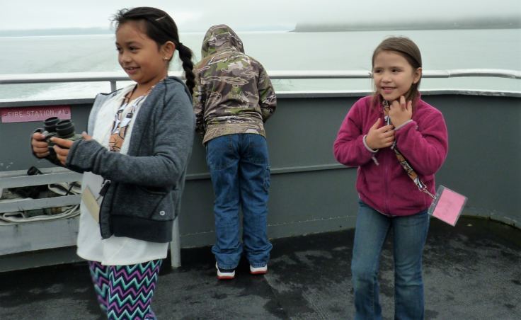 Children play on the back deck of the catamaran St. Peter during the tour of T’aaḵu Kwáan territory. (Photo by Ed Schoenfeld/CoastAlaska News)