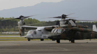 MV-22 Osprey, far left, and a helicopter on an airfield.