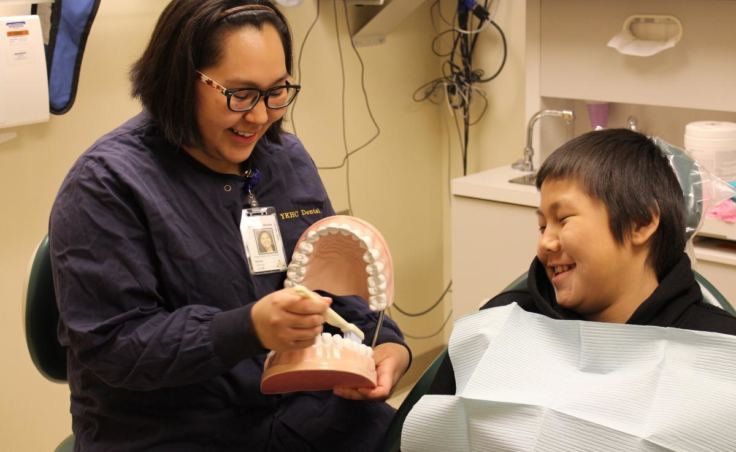 Dental health aide therapist Renee Cheek shows a patient how to brush his teeth at the Emmonak YKHC Sub-Regional Clinic. (Photo courtesy Yukon-Kuskokwim Health Corporation)