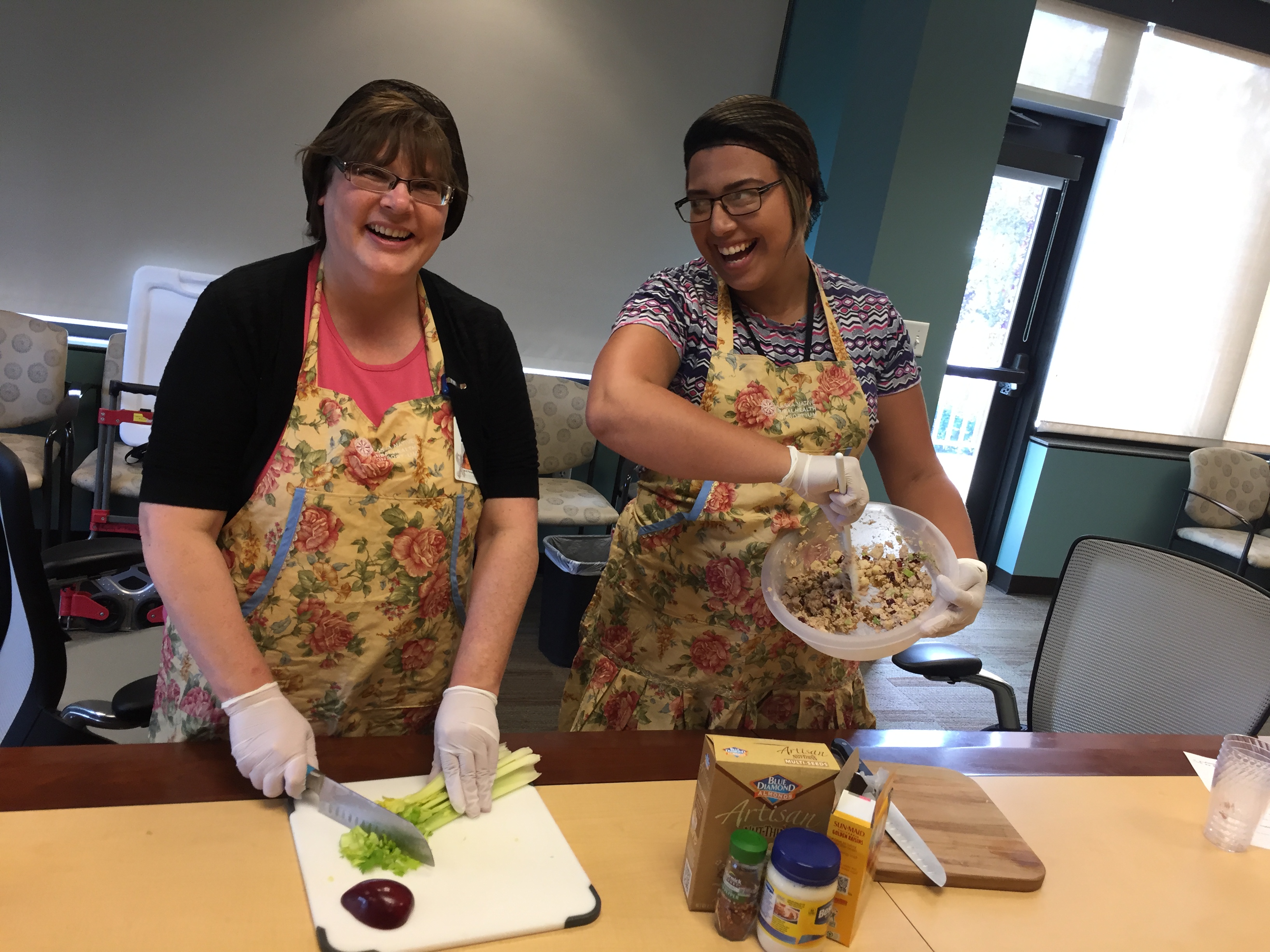 Marcia Anderson, left, and Karolyn Ceron demonstrate how to make fruity salmon salad at the Alaska Native Tribal Health Consortium. (Photo by Anne Hillman/Alaska Public Media)