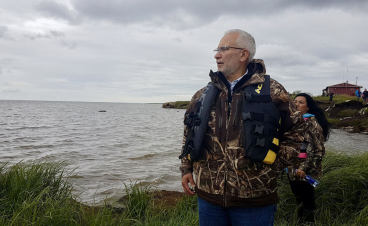 Carlton Kuhns, Assistant Superintendent to the Lower Kuskokwim School District, walks along a debris strewn shoreline of Newtok to the boats headed for Mertarvik. (Photo by Christine Trudeau/KYUK)