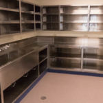 A shiny metal commercial kitchen area - counter and sink with shelves above and below it