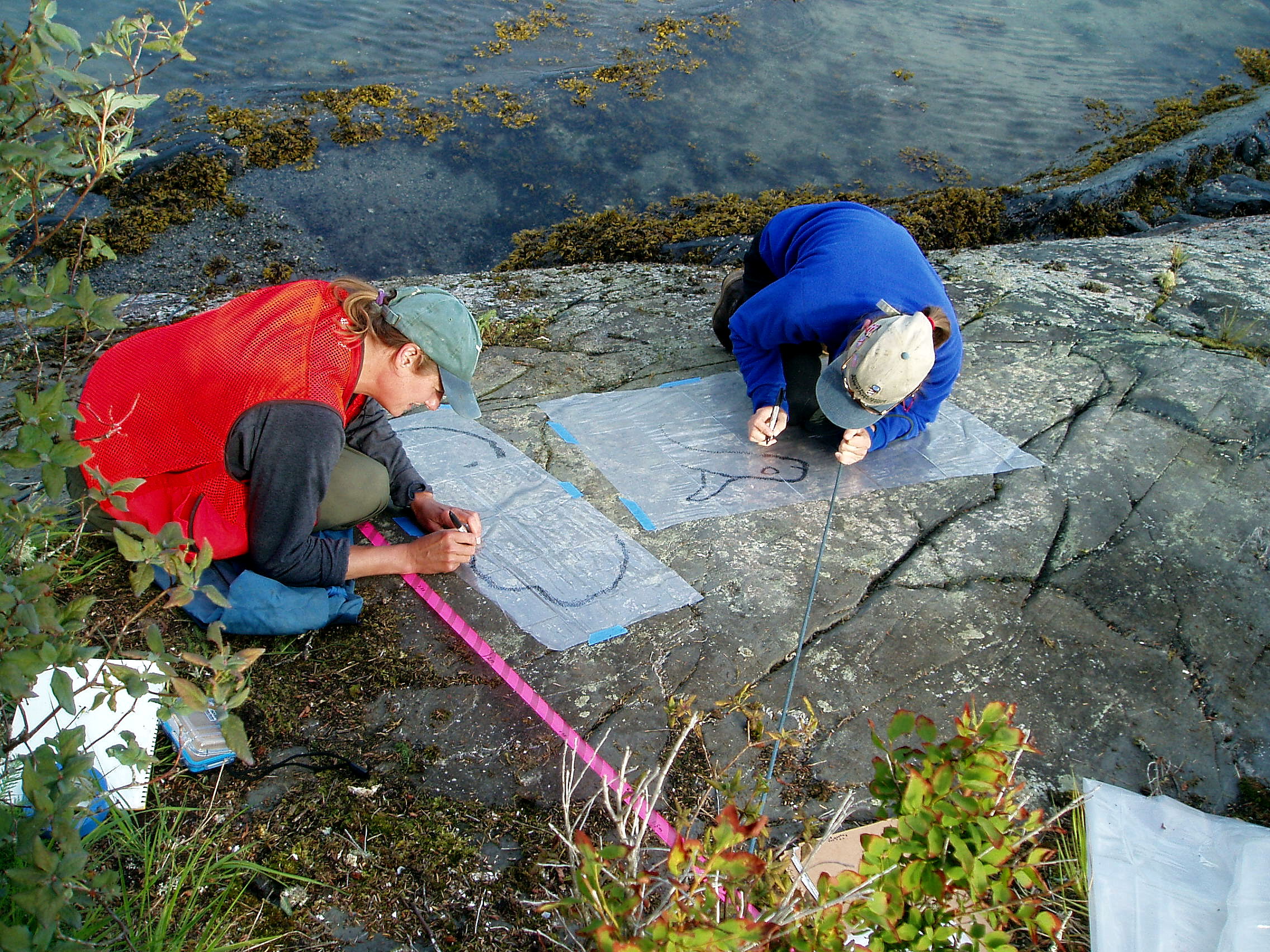 U.S. Forest Service Archaeologists, Jane Smith and Gina Esposito, record petroglyphs on the side of a rocky wall. (Photo courtesy of the U.S. Forest Service)