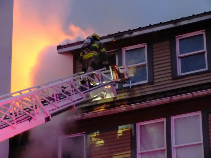 Capital City Fire/Rescue firefighter climbs a truck ladder to the third floor as fire continues to burn at 526 Seward Street on Sept. 17, 2017. (Photo by Matt Miller/KTOO)