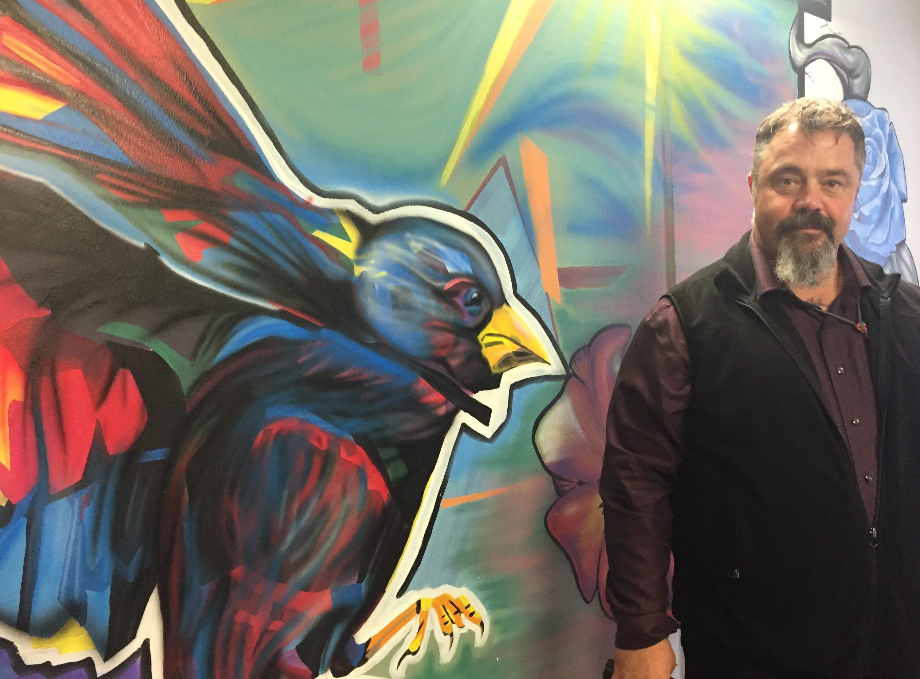 Spring Creek Superintendent Bill Lapinskas poses with one of the murals in the segregation housing at the Correctional Center. (Photo by Anne Hillman/Alaska Public Media)