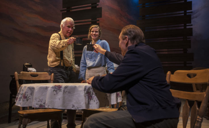 Joe Obach, played by actor Mike Peterson, Muz, actress Shelley Virginia) and John Barrymore, actor Peter DeLaurier, share a drink during rehearsal for "Dreaming Glacier Bay" on Wednesday, October 25, 2017 at Perseverance Theatre in Juneau, Alaska. (Photo by Rashah McChesney/Alaska's Energy Desk)