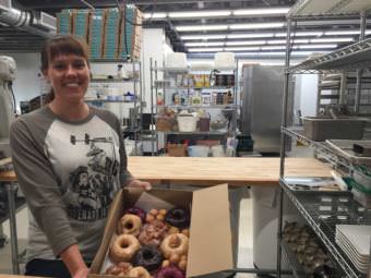 Laura Cameron displays some of the donuts from her new shop, Dipper Donut in Spenard. (Photo by Anne Hillman/Alaska Public Media)