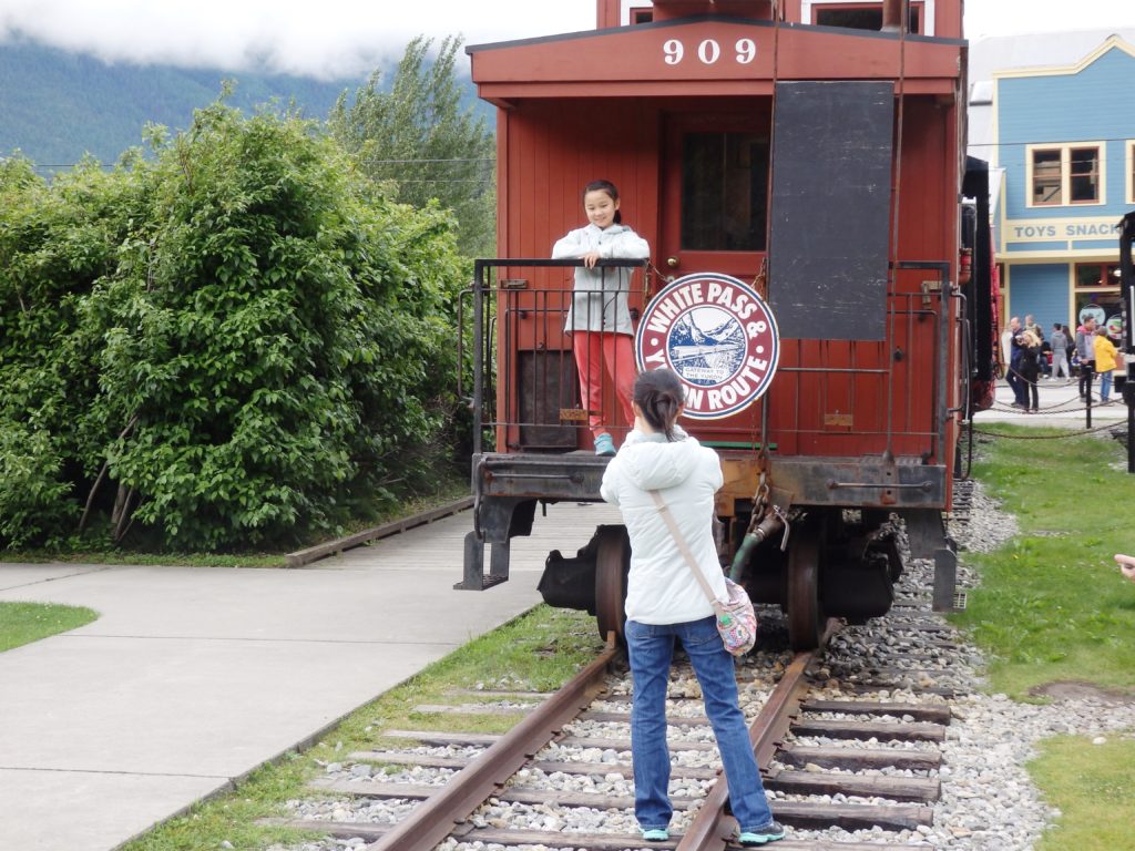 Tourists in Skagway take pictures with a White Pass and Yukon Route Railroad train car. (Photo by Emily Files/KHNS)