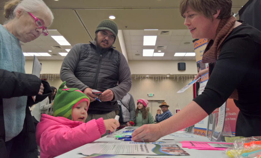 Jessie Menkens hands 3-year-old Mayzie Sheakley toothpaste and a toothbrush at a health care booth in Elizabeth Peratrovich Hall in Juneau on Friday, Nov. 24, 2017.