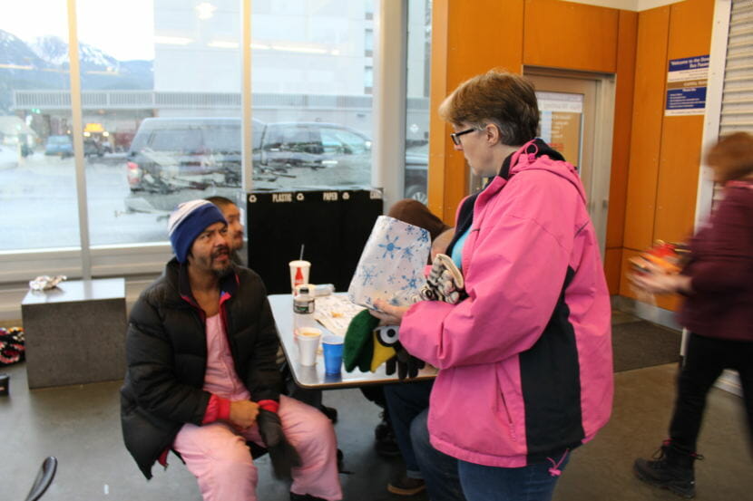 A volunteer gives William Denny a new hat to try out during lunch at the Downtown Transit Center in Juneau on Sunday, Dec. 10, 2017. 