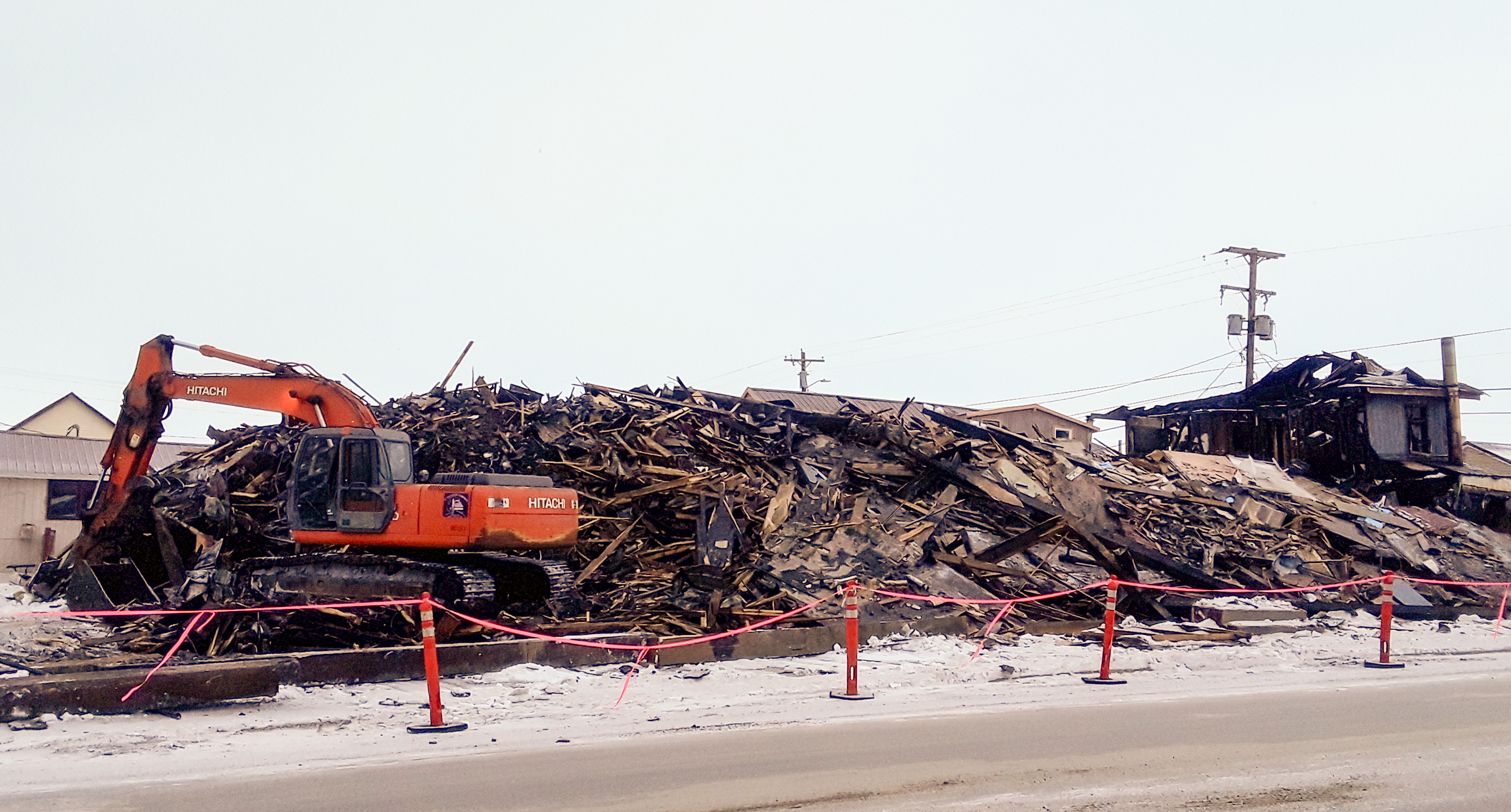 What remains of the Polaris Hotel in Nome is being demolished and removed by Q Trucking. (Photo by Davis Hovey/KNOM)