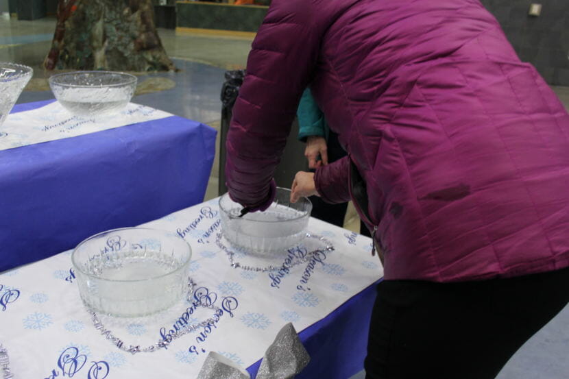 An attendee places a slip of paper with something they hope to let go of in the coming year into a bowl to let it dissolve at the Year of Kindness celebration on New Year's Eve. (Photo by Adelyn Baxter/KTOO)