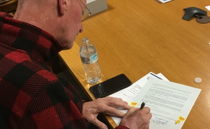 Ben Evans signs paperwork to become the new owner of the 55-year-old ferry Taku in Ketchikan on Jan. 19, 2018.