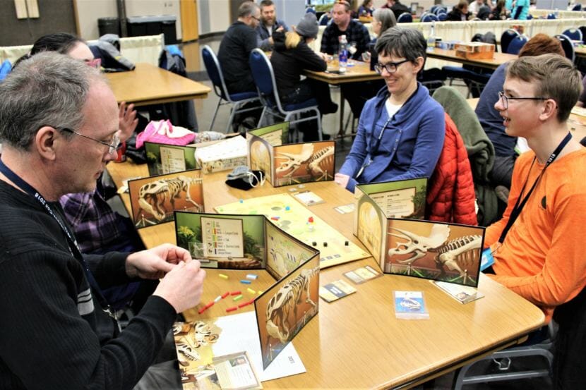 Peter Minick (left) and his wife Kim Champney (second from right) play The Great Dinosaur Rush with their daughter and a friend at Platypus Con on Jan. 28, 2018. (Photo by Adelyn Baxter/KTOO)