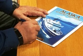 An official signs a poster of the ferry Taku at a ceremony for the sale of the ferry at Alaska Marine Highway headquarters in Ketchikan on Friday, Jan. 19, 2018.