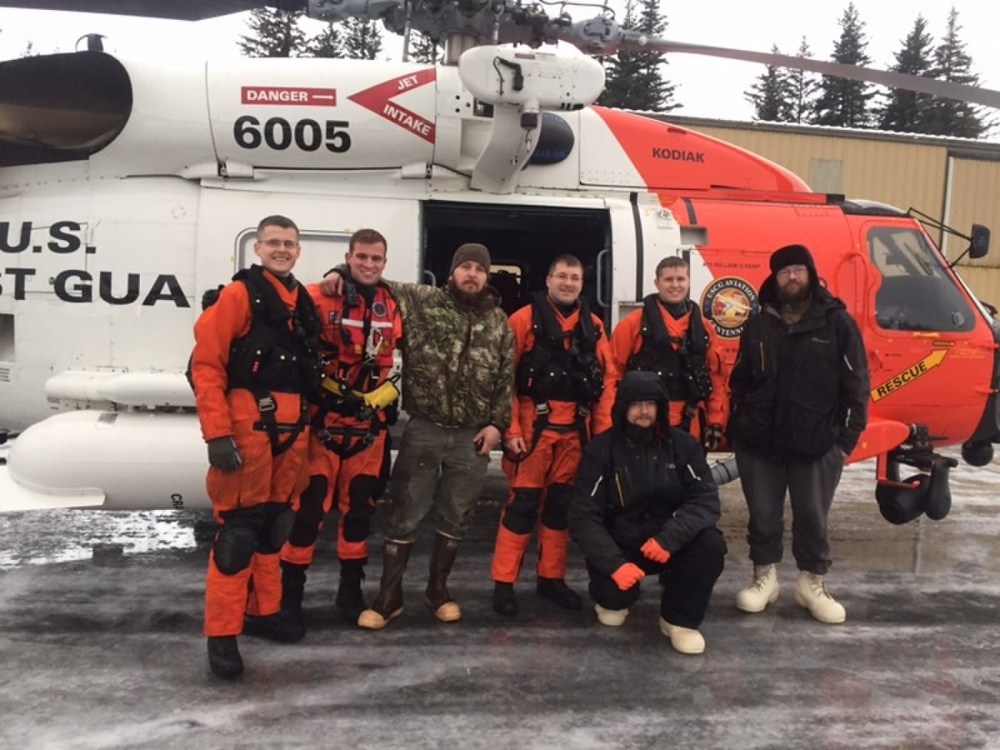 The three men rescued posing with the aircrew that found them. (Photo by Lt. Brian Dykens/Coast Guard)