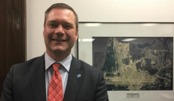 Ted Stevens Anchorage International Airport General Manager Jim Szczesniak stands in front of an aerial photo of the airport in the Capitol on Feb. 20, 2018. He said he would like to see the airport build on its role in global cargo transport.