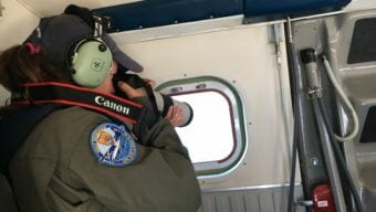 Melanie White takes photos of North Atlantic right whales from NOAA's Twin Otter as the plane circles the whales near Savannah. Whale observers and researchers use the photos to identify the whales. (Photo by Molly Samuel/WABE)