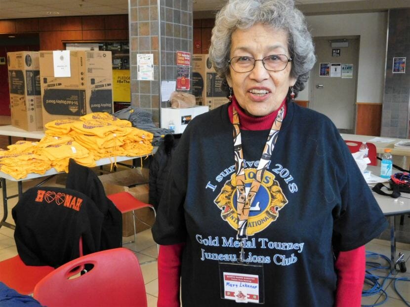 Mary Lekanof is a Juneau Lions Club member who volunteers before and during the Gold Medal games. Here's she works at the merchandise table. (Photo by Ed Schoenfeld/CoastAlaska News)