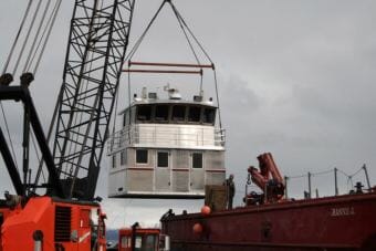 A crane moves an aluminum replacement cabin made by Homer's Bay Weld Boats. The company is one of a number of Alaska businesses already affected by President Trump's imported metals tariffs.