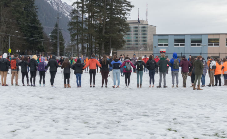 Students link arms for a moment of silence on a soccer field outside Juneau-Douglas High School during a walkout protest in Juneau on Wednesday, March 14, 2018.