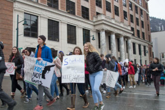 Students wave signs at a student walkout protest at the Alaska State Capitol building in Juneau on Wednesday, March 14, 2018.