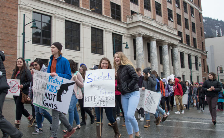 Students wave signs at a student walkout protest at the Alaska State Capitol building in Juneau on Wednesday, March 14, 2018.