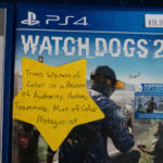 A video game box with a large yellow star stuck on the front. The star is labeled "Trans woman of color in a position of authority, autistic teammate, man of color protagonist"