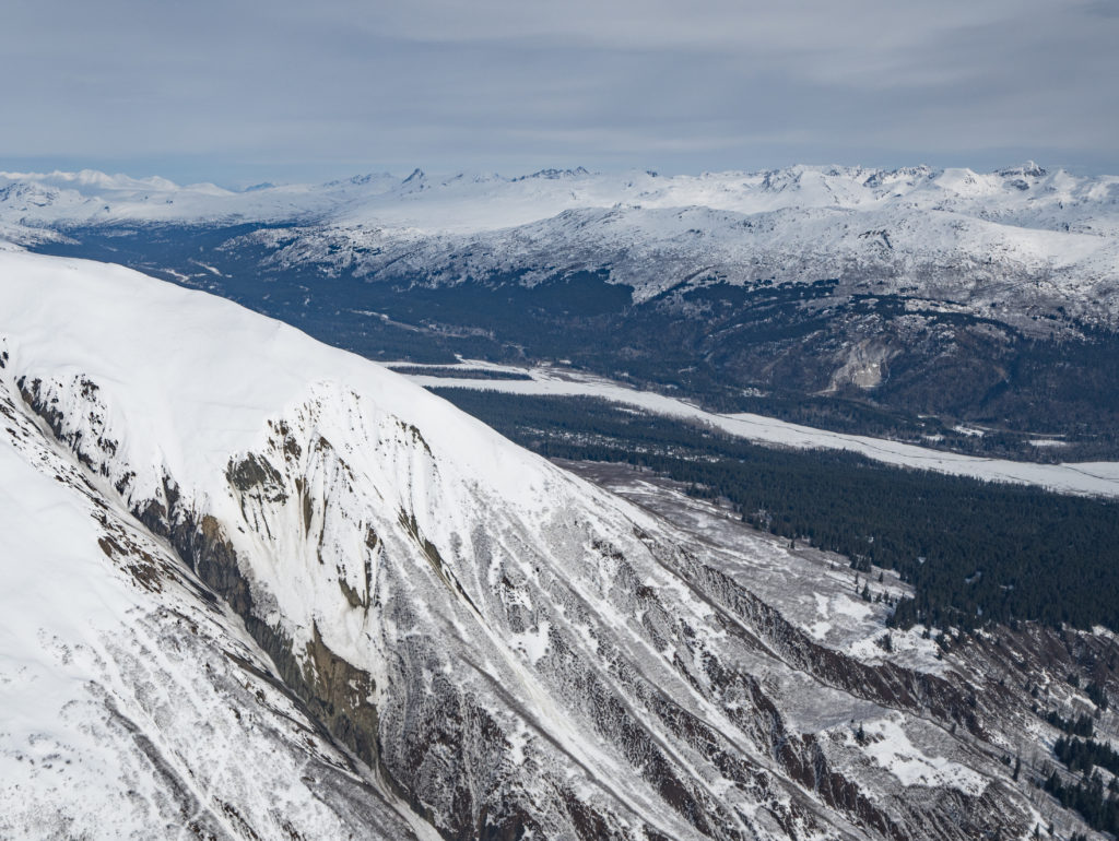 The Palmer mineral deposit is contained within the ridge in the left foreground. Viewpoint is looking northeast, up the Klehini River Valley and across the Canadian border. (Photo Courtesy of Takshanuk Watershed Council, Photo by Connor Gallagher)