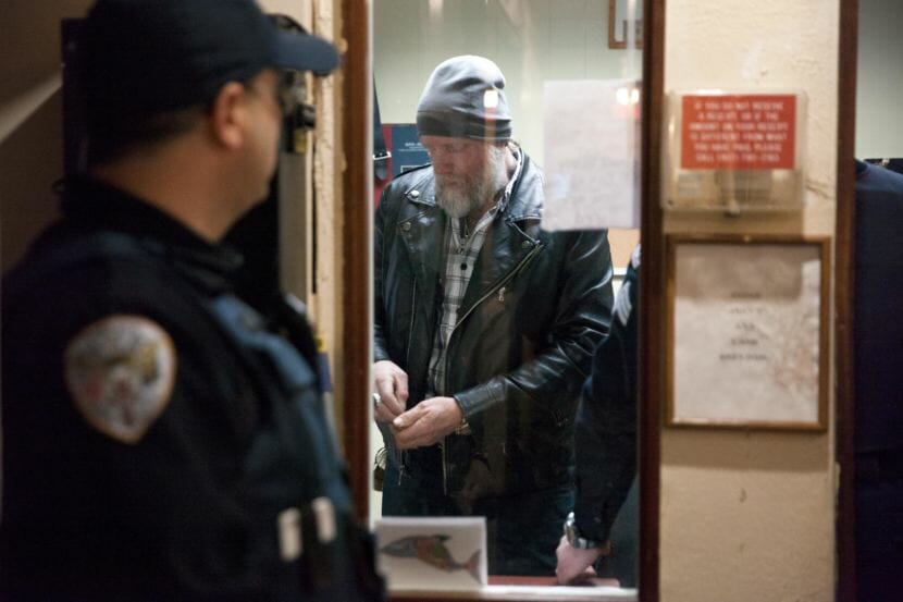 Juneau police officers confer as they arrest Chuck Cotten, property manager at the Bergmann Hotel. Cotten was responsible for removing residents from their rooms before Friday March 10, 2017 in Juneau, Alaska. The building was later condemned. (Photo by Rashah McChesney/Alaska's Energy Desk)