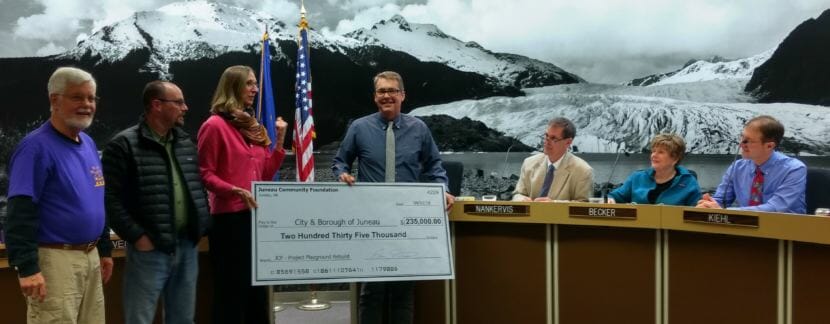 Juneau Community Foundation Executive Director Amy Skilbred presents Juneau City Manager Rorie Watt a novelty check for $235,000 in donations for Project Playground on April 2, 2018.