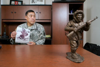 Then-Lt. Col. Wayne Don of the Alaska Army National Guard holds a photo of his uncle, Sam Herman, who served with the Alaska Territorial Guard during World War II in his office on Feb. 27, 2015. Herman is pictured during his subsequent service with the Alaska Army National Guard. A statuette of an ATG scout keeps vigil on Wayne's desk.
