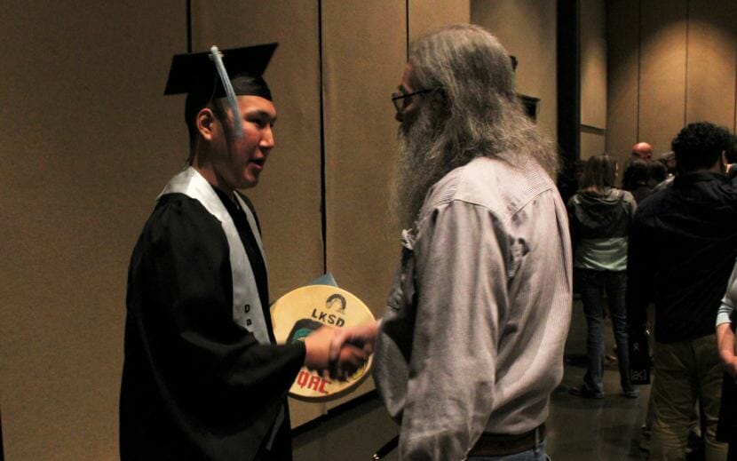 A community member congratulates Yaaḵoosgé Daakahídi High School graduate Byron Dock after the ceremony on Sunday. (Photo by Adelyn Baxter/KTOO)