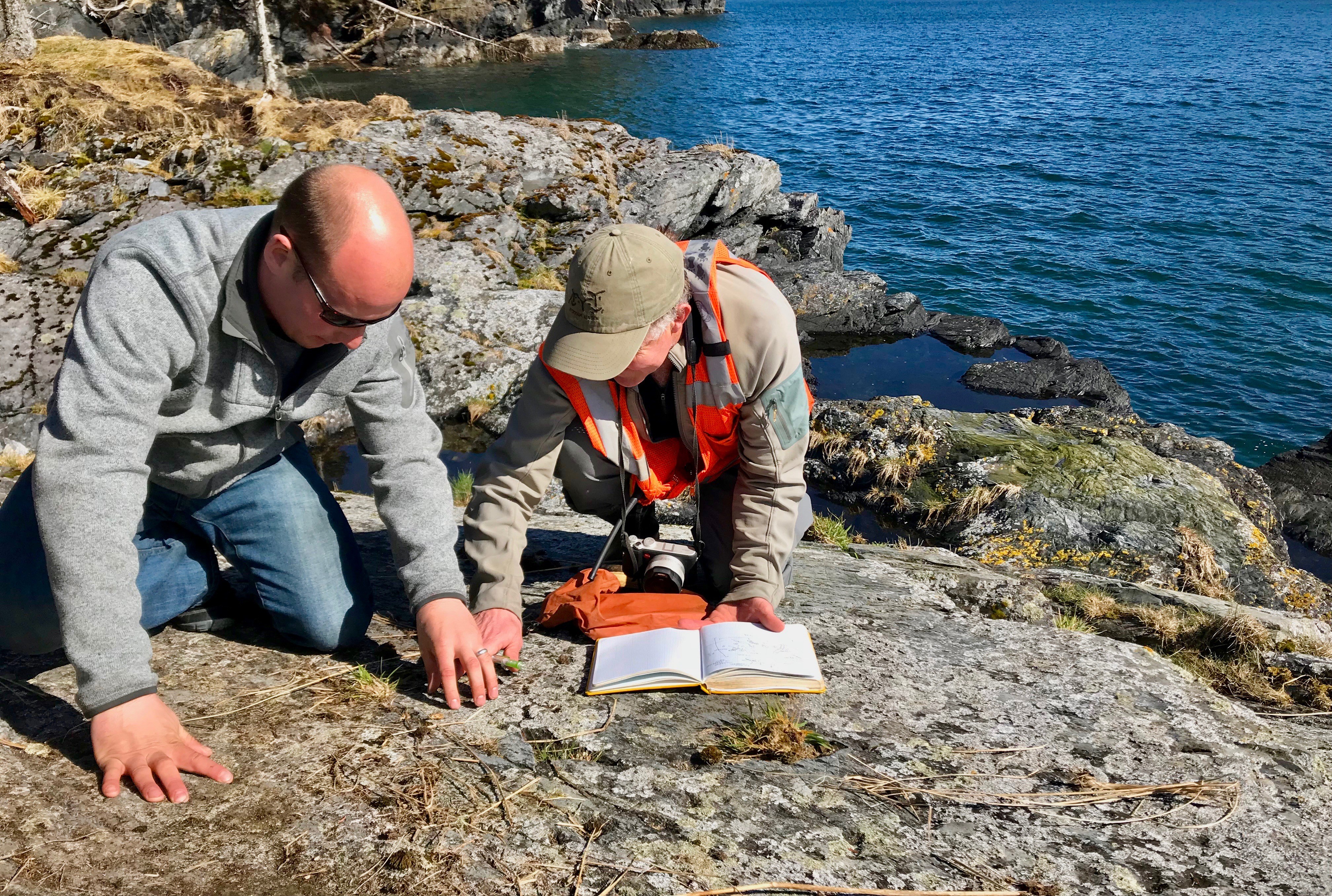 Museum archaeologist Patrick Saltonstall and helicopter pilot Keller Wattum document a petroglyph site on Afognak. (Photo courtesy Patrick Saltonstall)