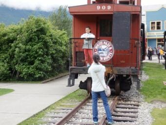 Tourists in Skagway take pictures with a White Pass and Yukon Route Railroad train car in 2017. (Photo by Emily Files/KHNS)