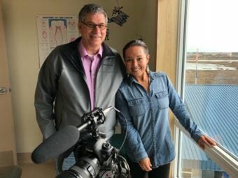 Indian Country Today editor Mark Trahant, left, and videographer Jacqueline Cleveland reporting for FIrst Nations Experience or FNX TV on the Dental Health Aide Therapist program housed at Yuut Elitnaurviat in Bethel. May 3, 2018. (Photo by Christine Trudeau/KYUK)
