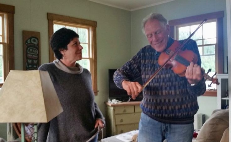 Avrum Gross plays the fiddle as his oldest daughter, Jody Gross, listens. Avrum was a Juilliard trained violinist as a youth, quit as an adult, but came back to it as a fiddler after moving to Alaska. (Photo courtesy Jody Gross)