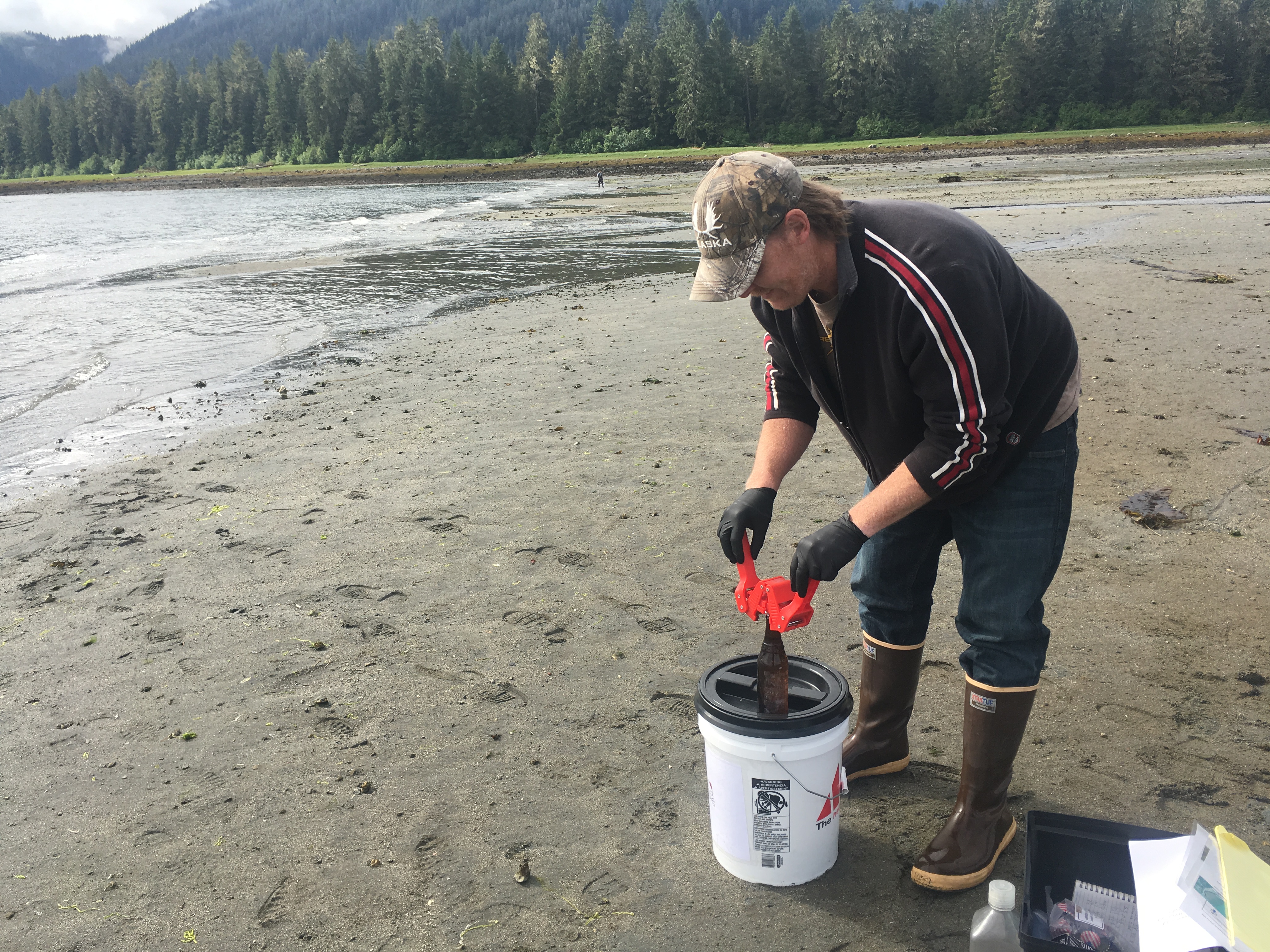 Petersburg Indian Association’s Brandon Thynes caps a bottle of ocean water at Sandy Beach. The sample is a part of Sitka Tribe’s efforts to study ocean acidification. (Photo by Alanna Elder/KFSK)