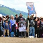 Members of the Yanyeidí clan hold pictures of their mothers and grandmothers as they watch the installation of the wolf totem pole at Savikko Park. June 6, 2018. (Photo by Adelyn Baxter/KTOO)